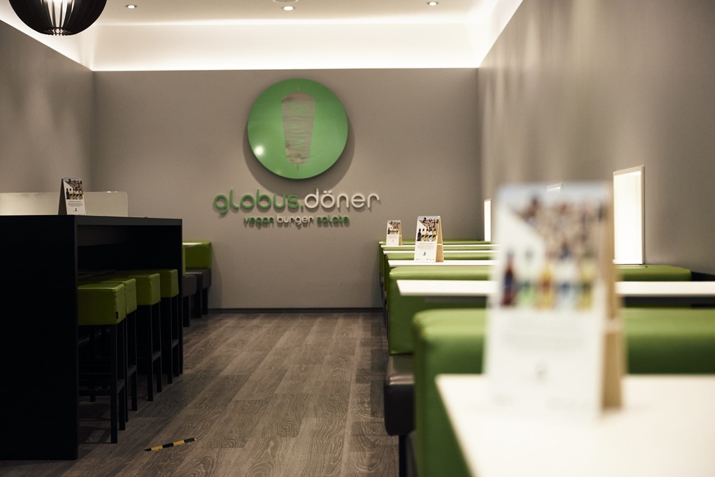 Globus Döner Filiale mit Tischen, Bänken und Logo an der Wand.