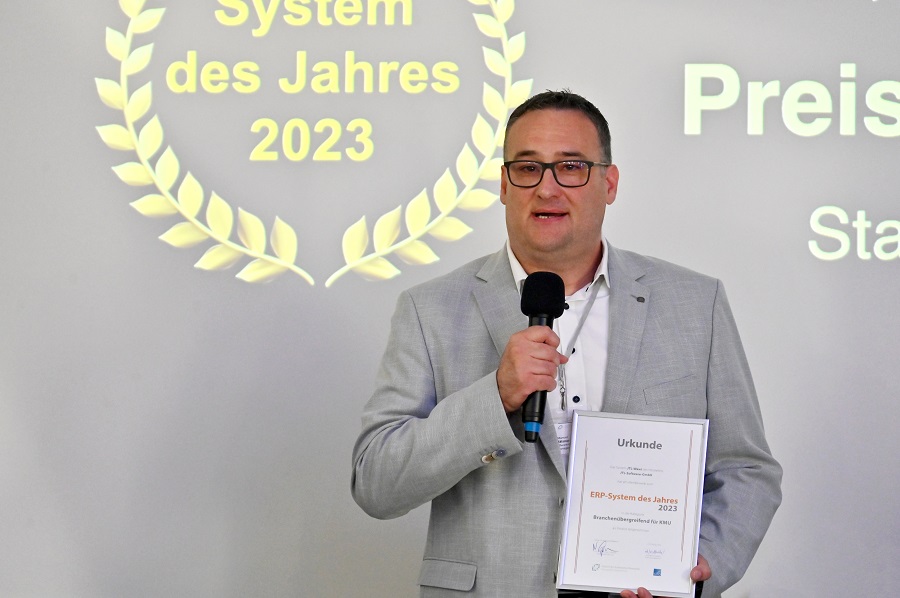 Manuel Mälzner von JTL hält auf der Preisverleihung die Urkunde ERP-System des Jahres 2023 in der Hand und spricht eine Dankesrede ins Mikrofon.