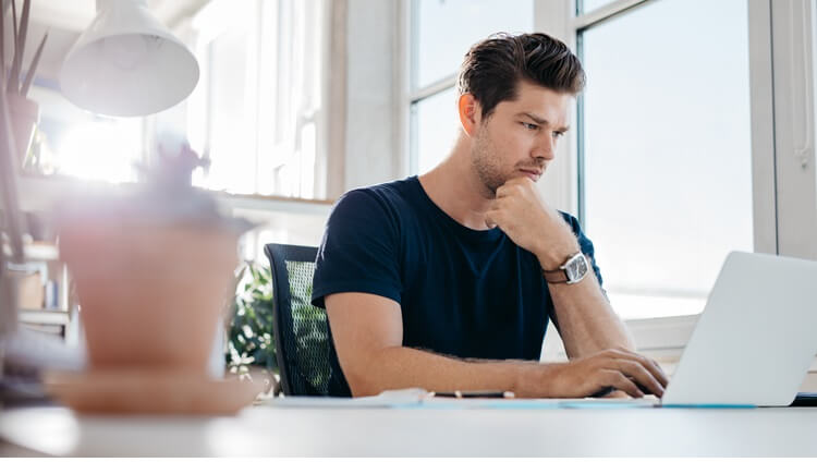 Junger Mann am Laptop nutzt Self Service bei Einkauf im Onlineshop.