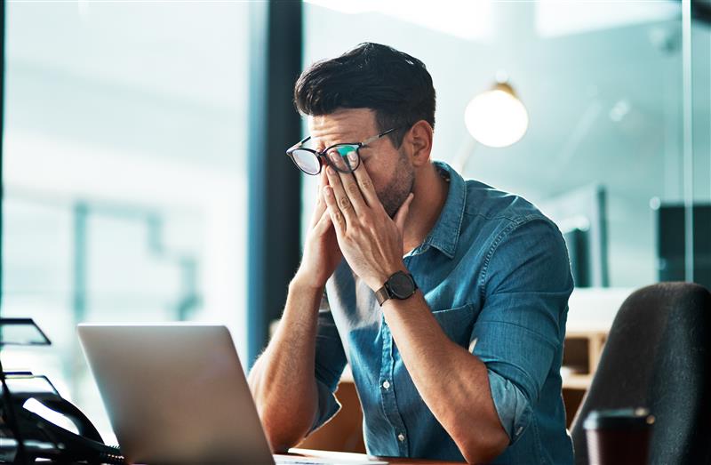 Gestresster junger Mann im Büro vor einem Laptop