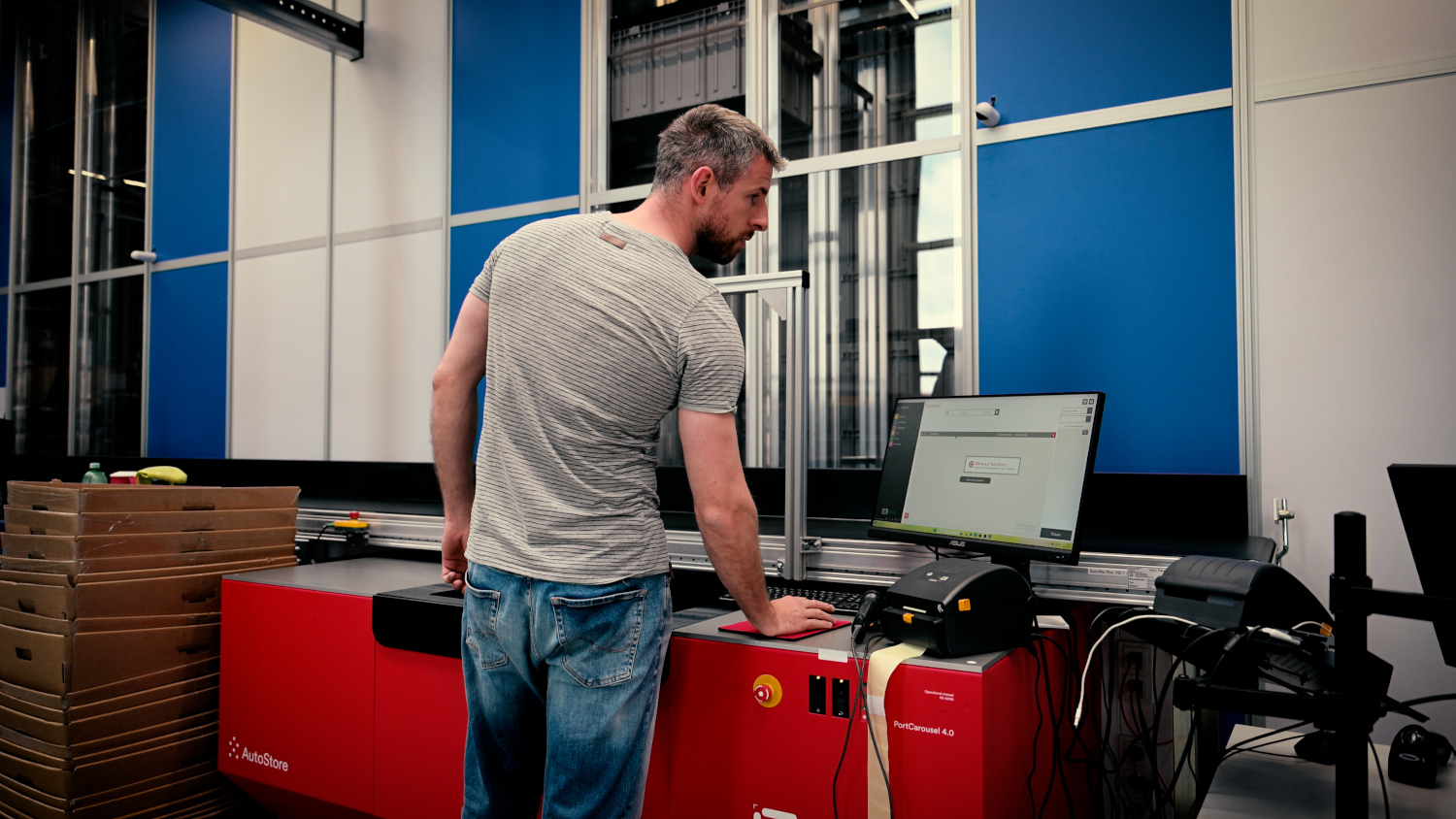 Mann steht an Computer vor AutoStore Lager-System